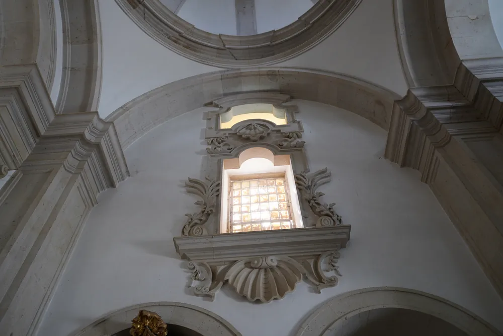Inside the chapel: a nave window with a shaped frame and shell ornament.